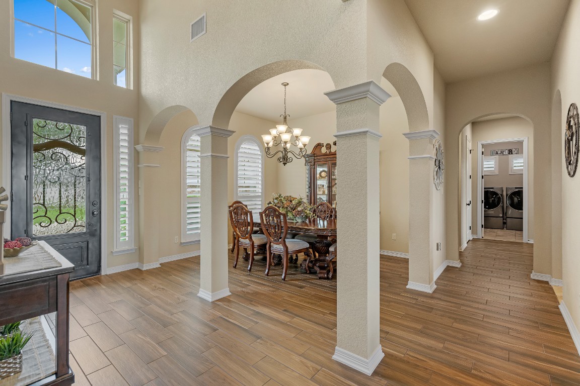 144 Indian Ridge Road Belton, TX 76513 - Photo 6 of 24 Foyer featuring arched walkways, light wood-style flooring, washer and clothes dryer, a chandelier, and a towering ceiling