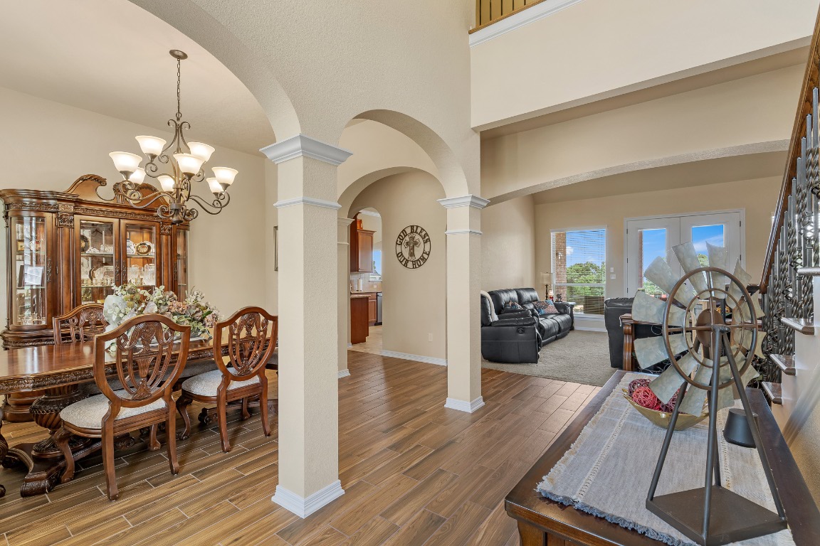 144 Indian Ridge Road Belton, TX 76513 - Photo 7 of 24 Dining space featuring arched walkways, a chandelier, wood tiled floors, ornate columns, and a high ceiling