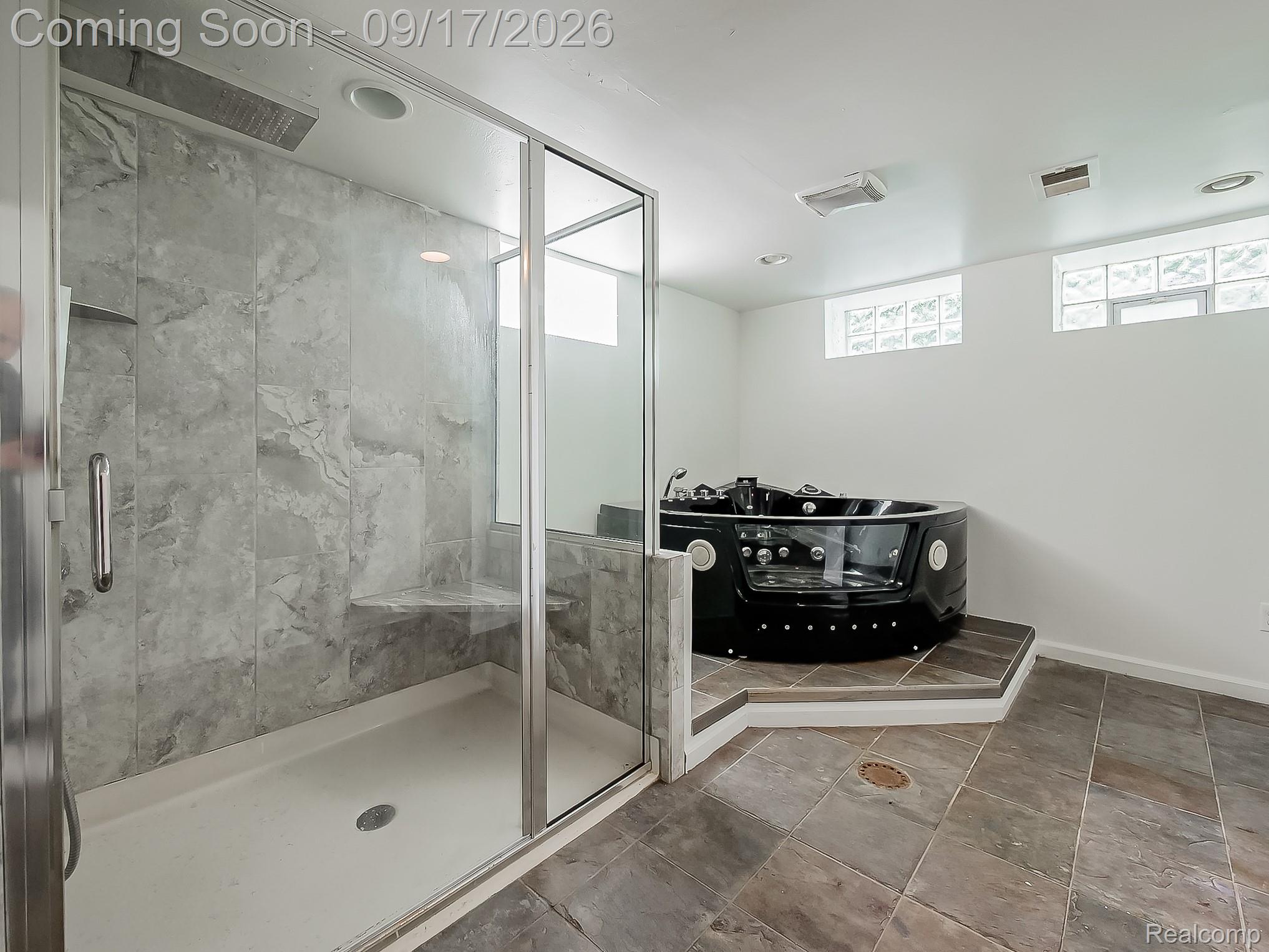 14102 Toepfer Road Warren, MI 48089 - Photo 21 of 39 Glass-enclosed shower with stone-finish tile surround and built-in bench, black jetted tub, and block windows