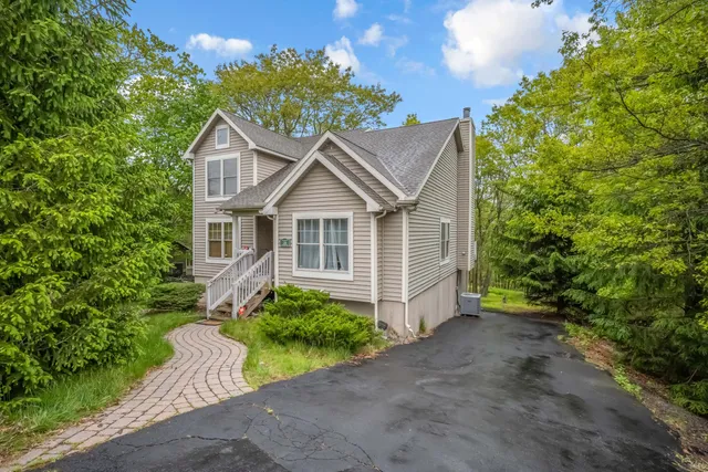 a view of a house with a small yard plants and large tree