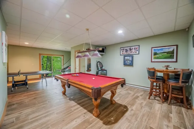 a room with furniture pool table wooden floor and windows
