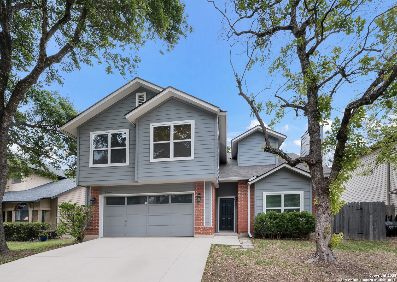 a front view of a house with a garden and tree