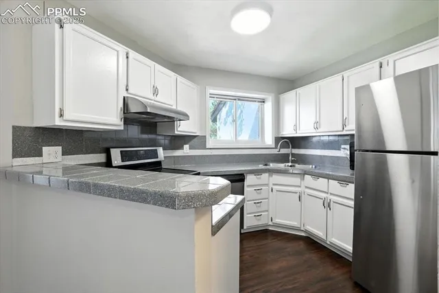 a kitchen with stainless steel appliances granite countertop a refrigerator sink and white cabinets