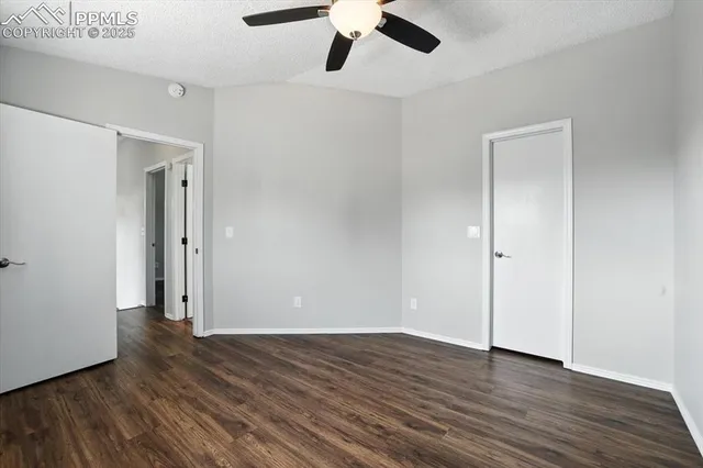 an empty room with wooden floor and a ceiling fan