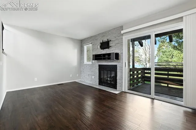 an empty room with wooden floor fireplace and windows