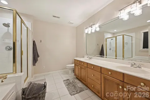 a spacious bathroom with a granite countertop sink a toilet a mirror and shower