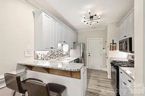 a kitchen with kitchen island granite countertop a sink cabinets and stainless steel appliances