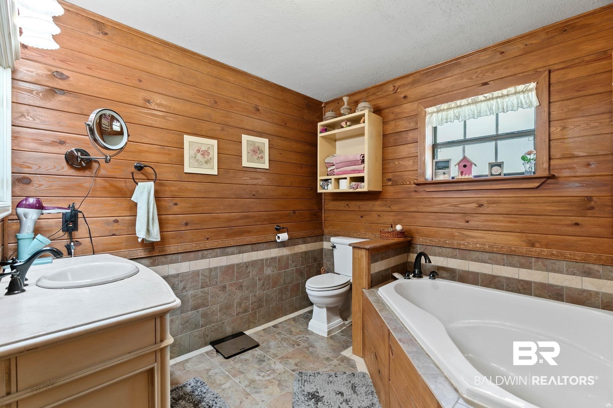 724 Rowell Lane Brewton, AL 36426 - Photo 20 of 40 Full bath featuring a bath, wooden walls, a wainscoted wall, vanity, and tile walls