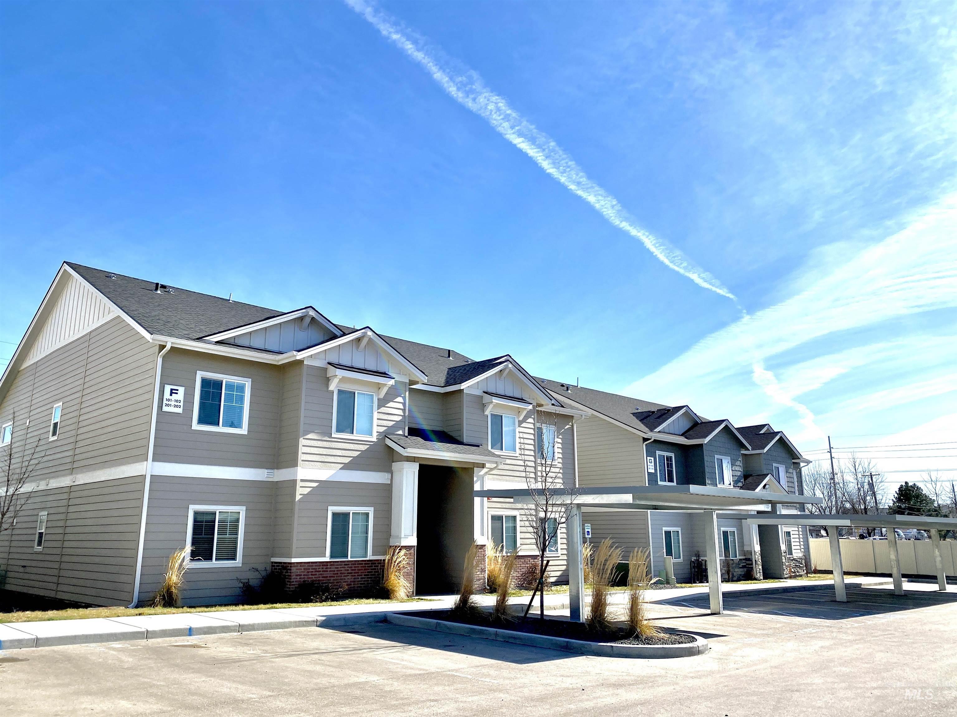 View of front of house with board and batten siding, brick siding, roof with shingles, and covered parking