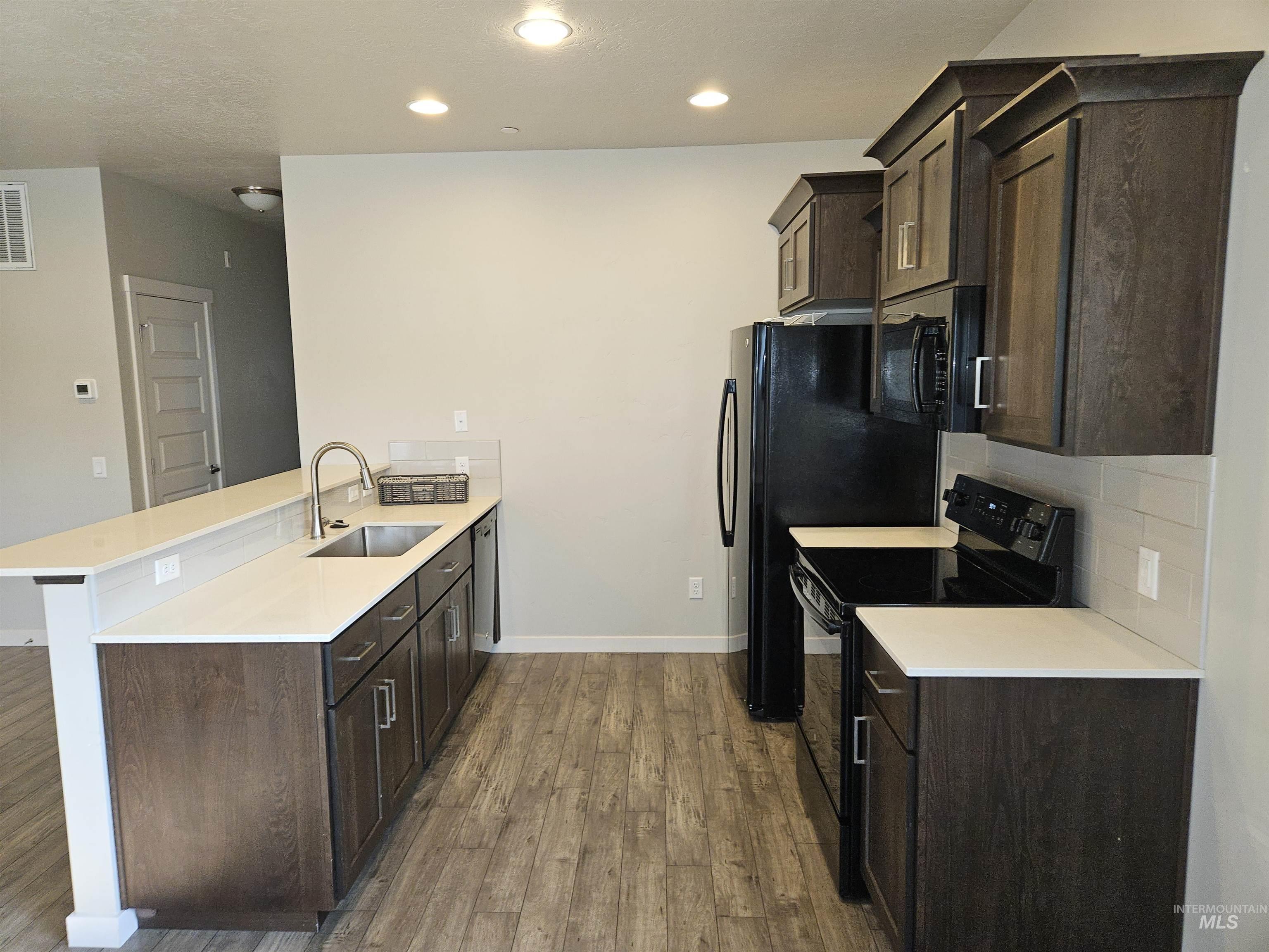 324 Northwest 3rd Street Meridian, ID 83642 - Photo 5 of 13 Kitchen featuring dark wood finish cabinetry, black appliances, a peninsula, dark wood-type flooring, and recessed lighting