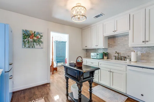 a kitchen with stainless steel appliances granite countertop a stove a sink dishwasher and a refrigerator with wooden floor