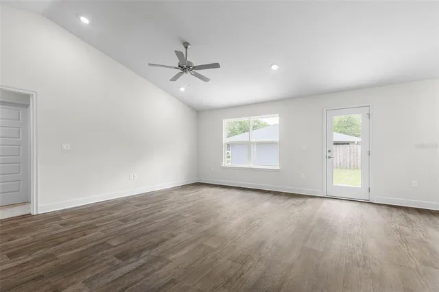 an empty room with wooden floor fan and windows
