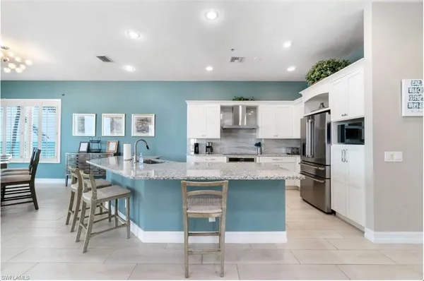 a kitchen with kitchen island wooden cabinets and refrigerator
