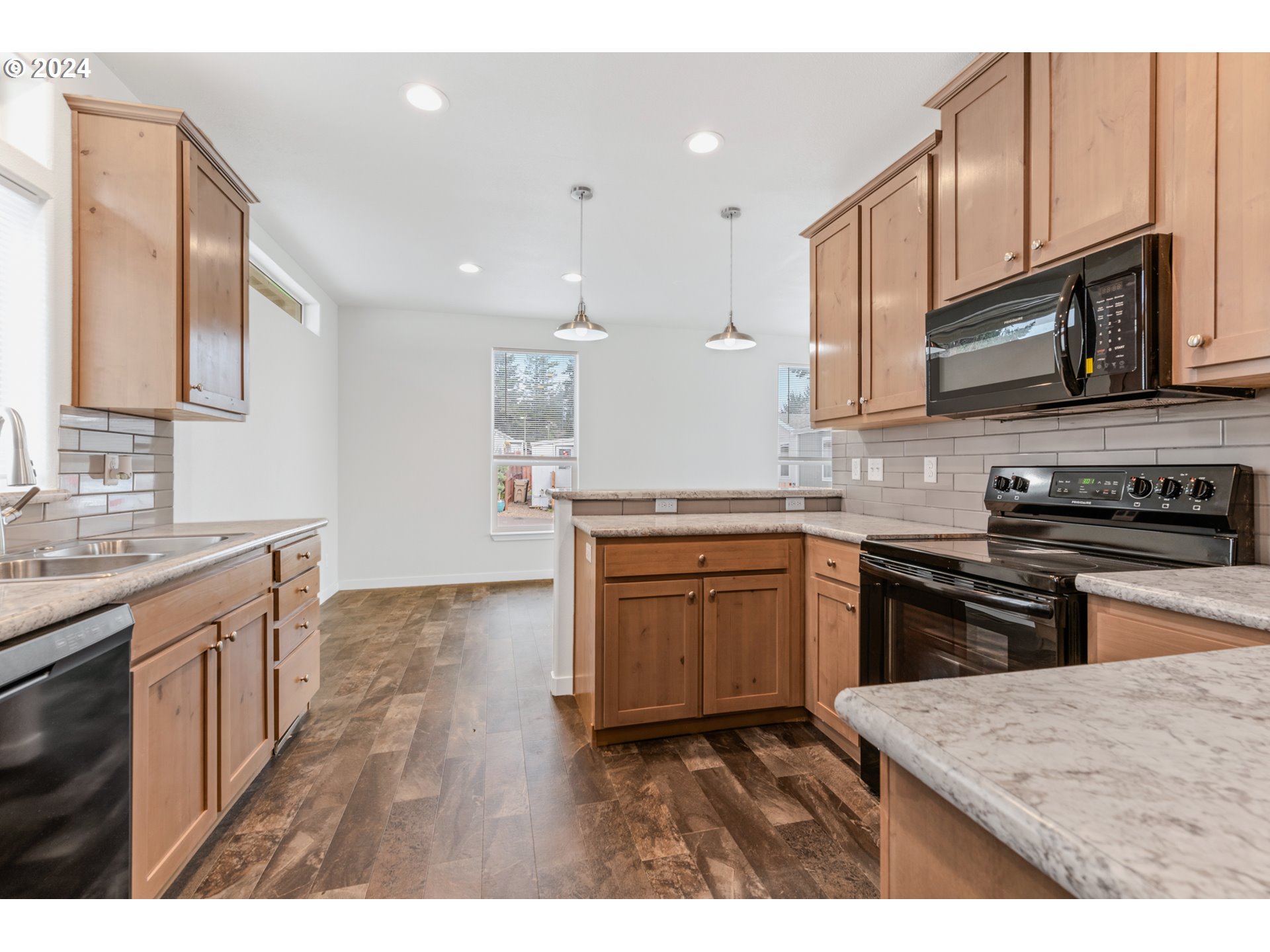 9700 Southwest Tualatin Road, Unit 22 Tualatin, OR 97062 - Photo 11 of 30 a kitchen with stainless steel appliances granite countertop a stove top oven a sink dishwasher and wooden cabinets with wooden floor