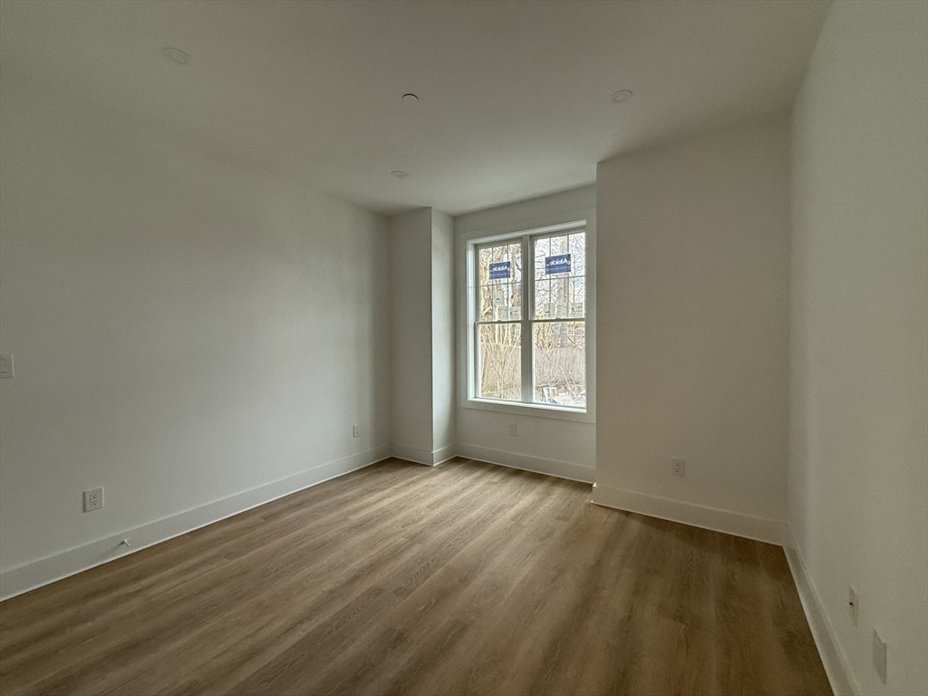 49 Chase Street, Unit 3 Newton, MA 02459 - Photo 7 of 12 an empty room with wooden floor and windows