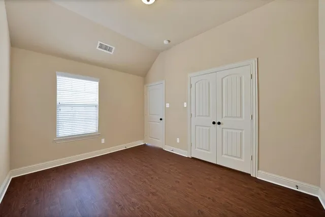 an empty room with wooden floor and window