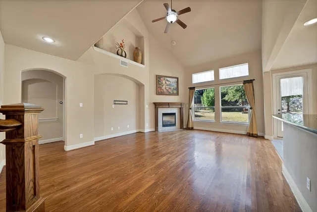 a view of a livingroom with wooden floor a ceiling fan and windows