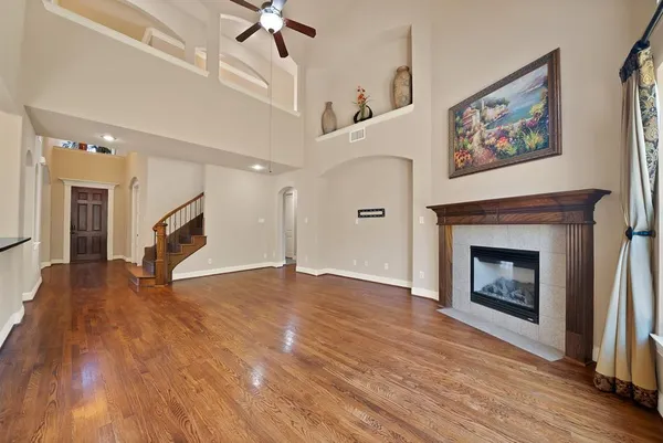 a view of an empty room with wooden floor fireplace and a window