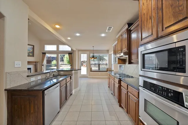a large kitchen with stainless steel appliances granite countertop a stove and a sink