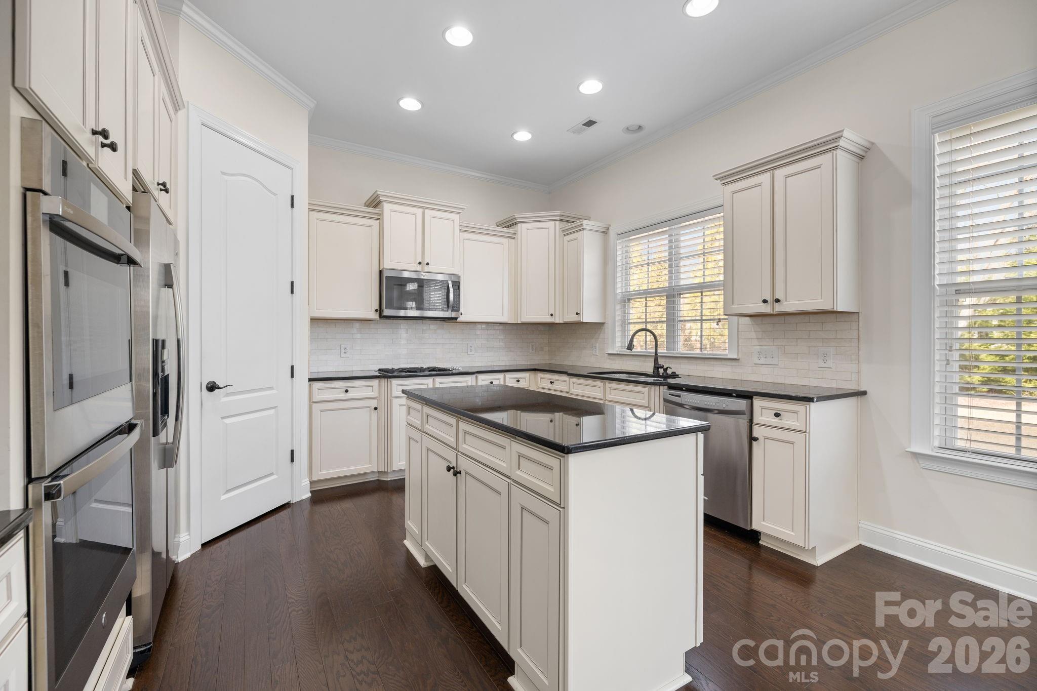 646 Quicksilver Trail Fort Mill, SC 29708 - Photo 16 of 48 a kitchen with stainless steel appliances granite countertop a stove a sink dishwasher a refrigerator white cabinets and wooden floor