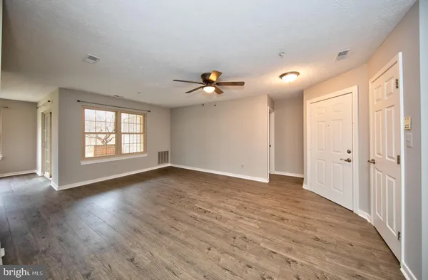 a view of an empty room with a window and wooden floor
