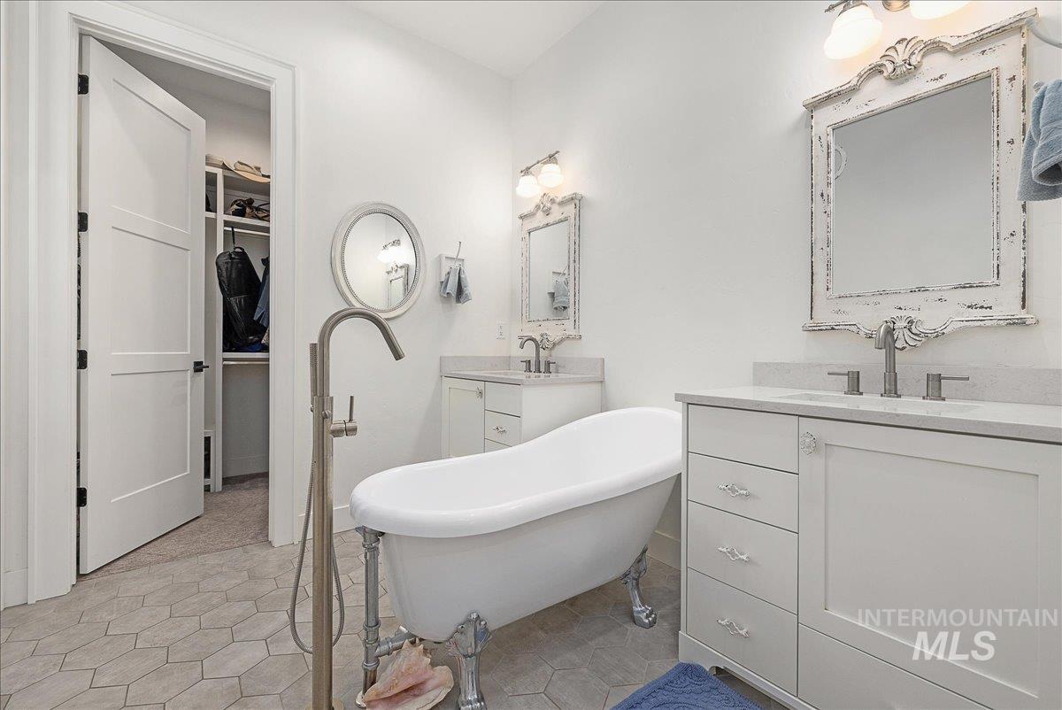 24301 Wanda Way Middleton, ID 83644 - Photo 20 of 50 Bathroom featuring a soaking tub, light tile patterned floors, two vanities, and a walk in closet