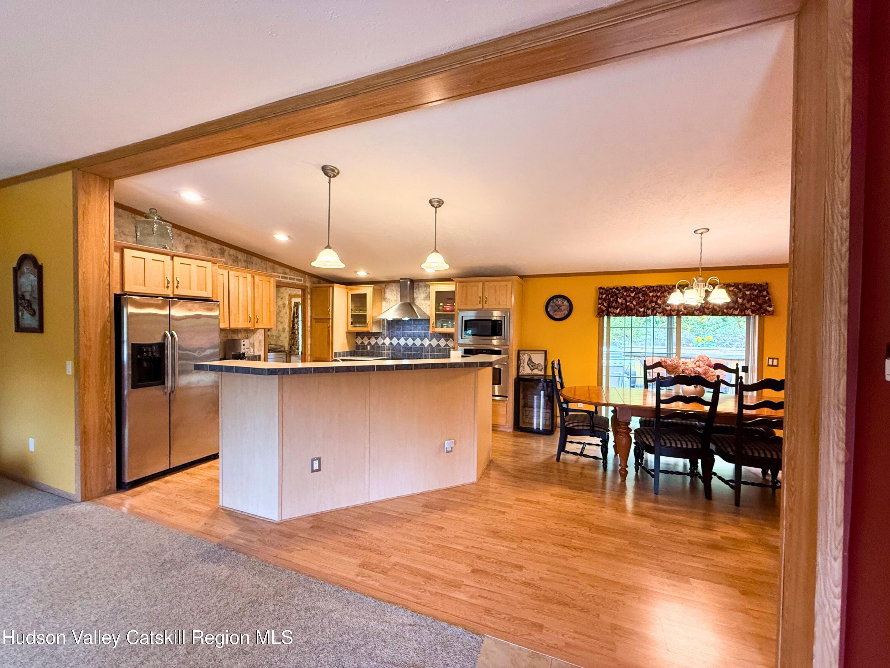 766 Hog Mountain Circle Fleischmanns, NY 12430 - Photo 10 of 31 a open kitchen with stainless steel appliances kitchen island granite countertop a table chairs and a view of living room