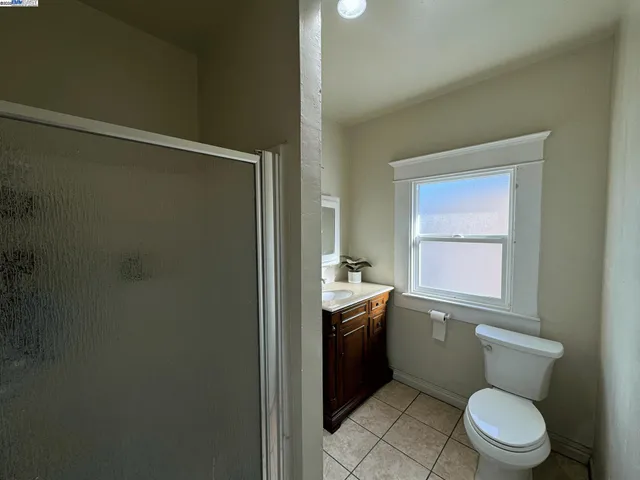 a bathroom with a granite countertop toilet a sink a mirror and a shower