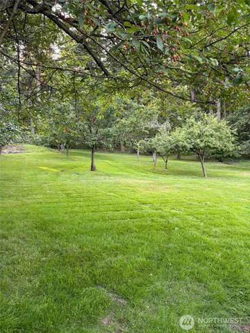 a view of a brick house with a big yard and large trees