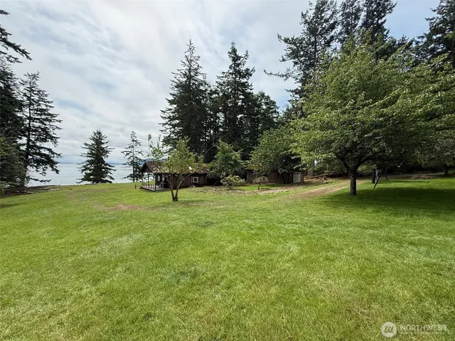 a view of a house with a big yard and large trees