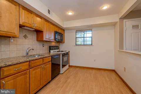 a kitchen with granite countertop a stove a sink and a microwave