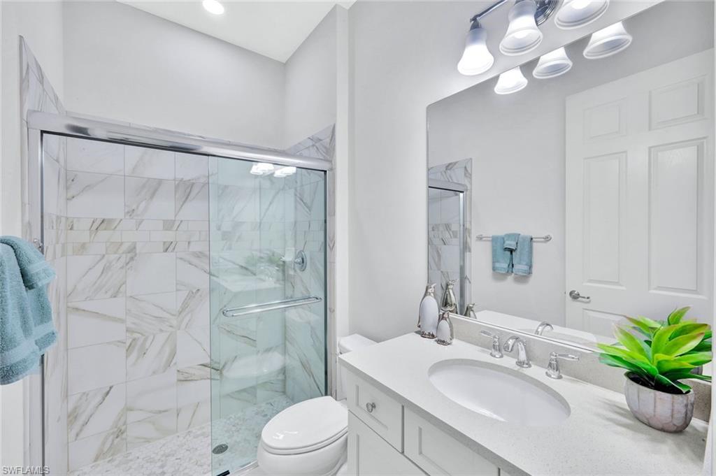 9311 Fieldstone Lane Naples, FL 34120 - Photo 23 of 48 a spacious bathroom with a granite countertop sink a toilet a mirror a vanity and shower