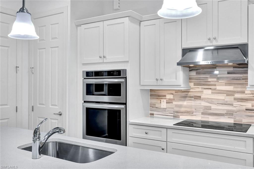 9311 Fieldstone Lane Naples, FL 34120 - Photo 9 of 48 a kitchen with white cabinets and a sink