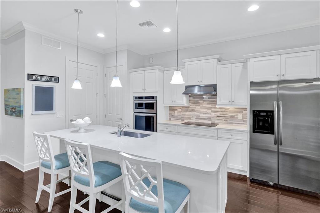 9311 Fieldstone Lane Naples, FL 34120 - Photo 10 of 48 a kitchen with stainless steel appliances kitchen island granite countertop a dining table chairs refrigerator and microwave