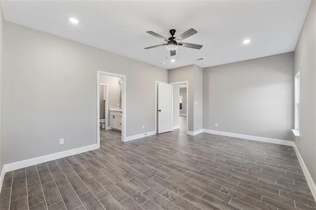 a view of an empty room with wooden floor and a ceiling fan