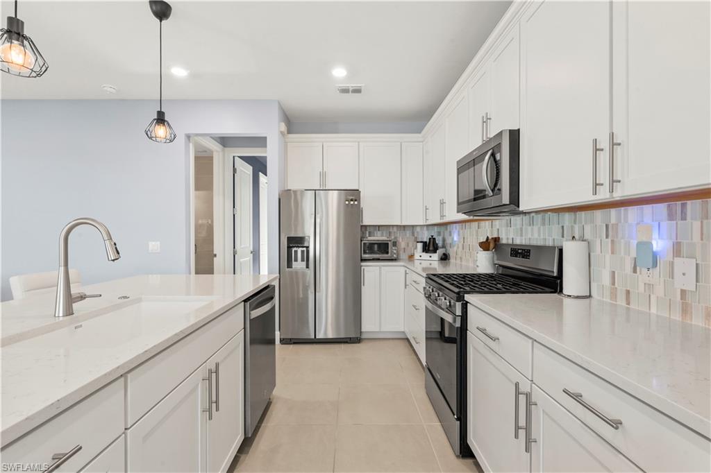20250 Napa Loop Estero, FL 33928 - Photo 7 of 33 a kitchen with stainless steel appliances granite countertop a refrigerator sink and white cabinets