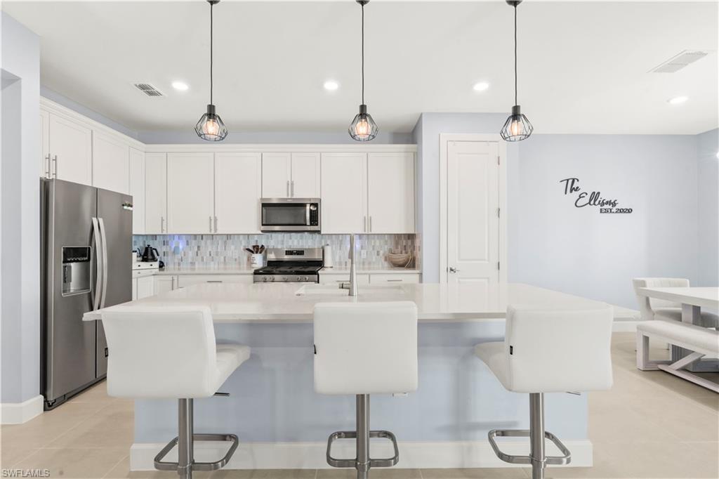 20250 Napa Loop Estero, FL 33928 - Photo 8 of 33 a kitchen with stainless steel appliances granite countertop a refrigerator a stove a sink dishwasher a dining table and chairs with wooden floor