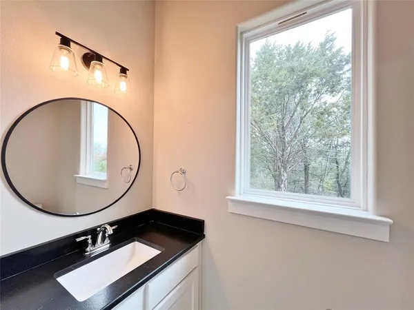 a bathroom with a sink mirror and a window