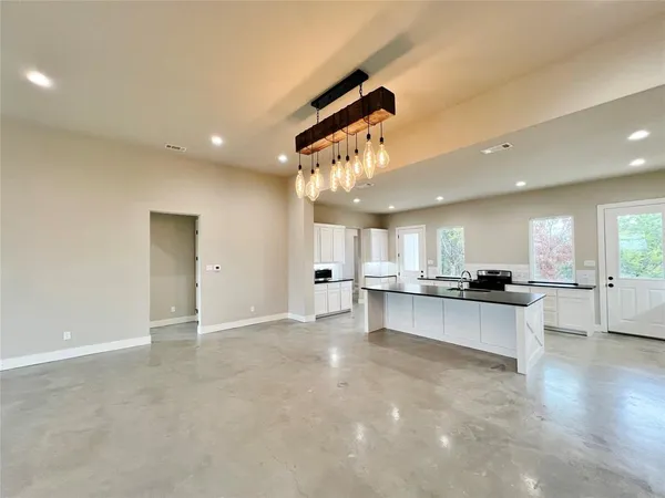 a large kitchen with a large counter top space a sink stainless steel appliances and cabinets