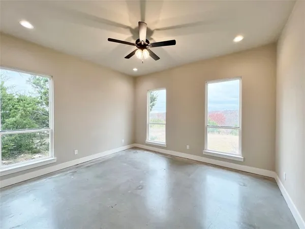 an empty room with wooden floor fan and windows