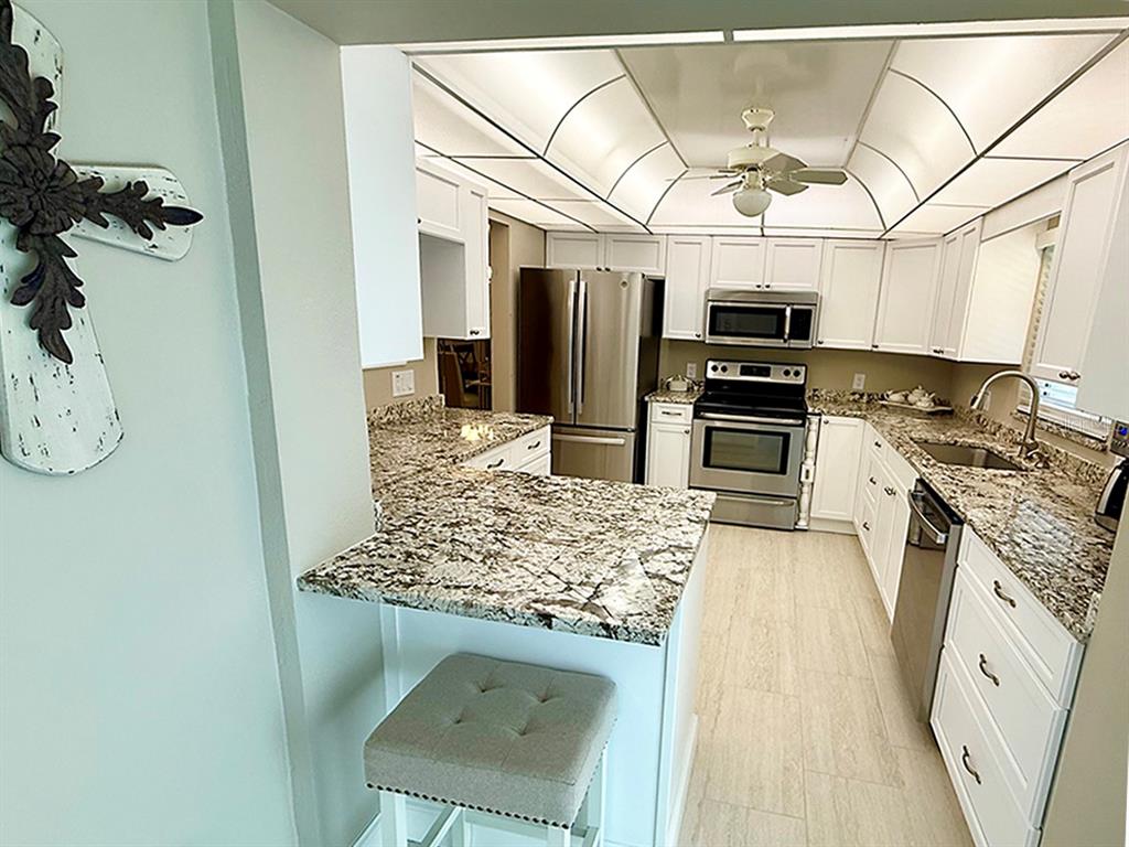 4455 Duhme Road, Unit 103 St. Petersburg, FL 33708 - Photo 7 of 37 a kitchen with stainless steel appliances granite countertop a sink stove and refrigerator