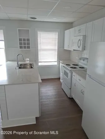 a kitchen with granite countertop white cabinets and white appliances