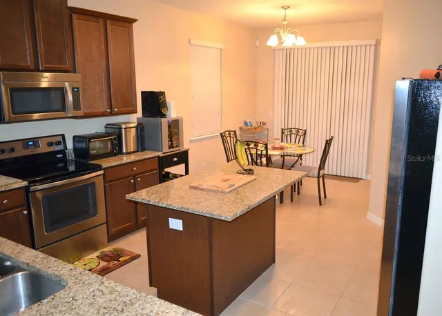 a kitchen with stainless steel appliances granite countertop a refrigerator a stove and white cabinets