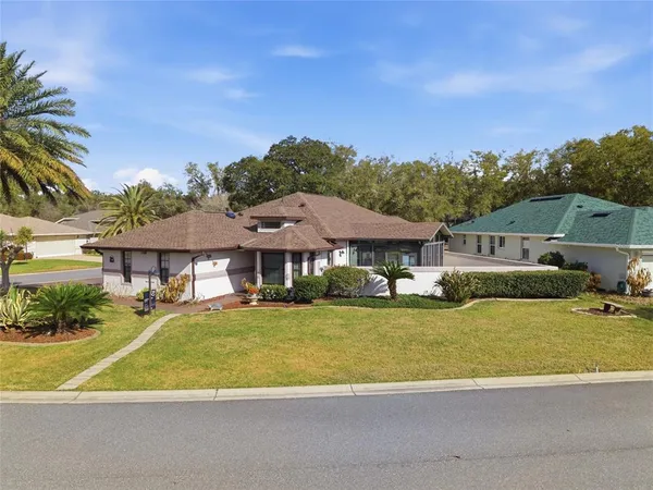 a view of a big house with a big yard and large trees