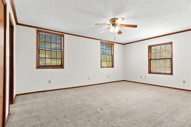 an empty room with windows and ceiling fan