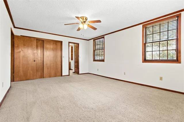 an empty room with windows and fan
