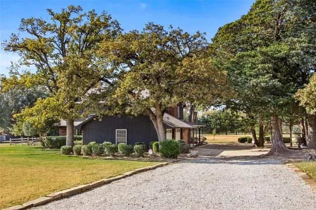 a view of a house with a yard and large trees