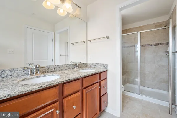 a bathroom with a granite countertop sink mirror and a shower