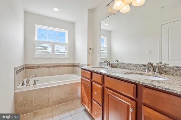 a bathroom with a granite countertop sink and a bathtub