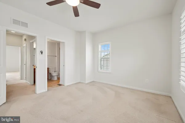 an empty room with chandelier fan and windows